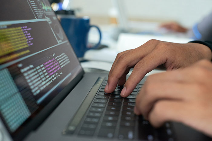 A man types on a laptop, coding with focus, possibly symbolizing frustration over Wi-Fi issues.