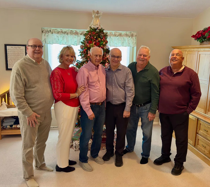 Dixon Handshaw reunites with family after 75 years, standing together by a decorated Christmas tree in a cozy living room.