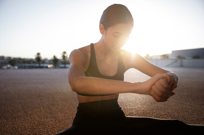 Woman practicing yoga outdoors at sunrise, demonstrating body life hacks.
