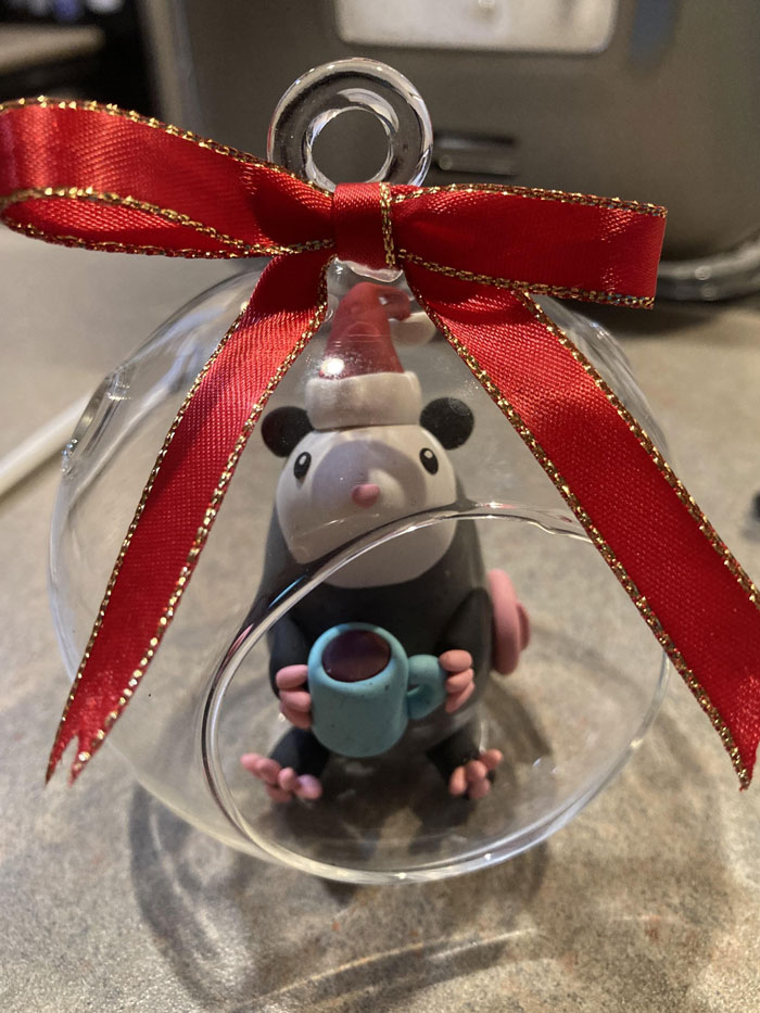 DIY Christmas decoration featuring a figurine in a clear ornament with a red ribbon.