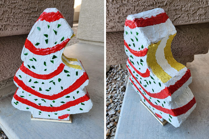 DIY Christmas decoration, a colorful, layered cardboard tree with red, white, and green accents, on a cement surface.