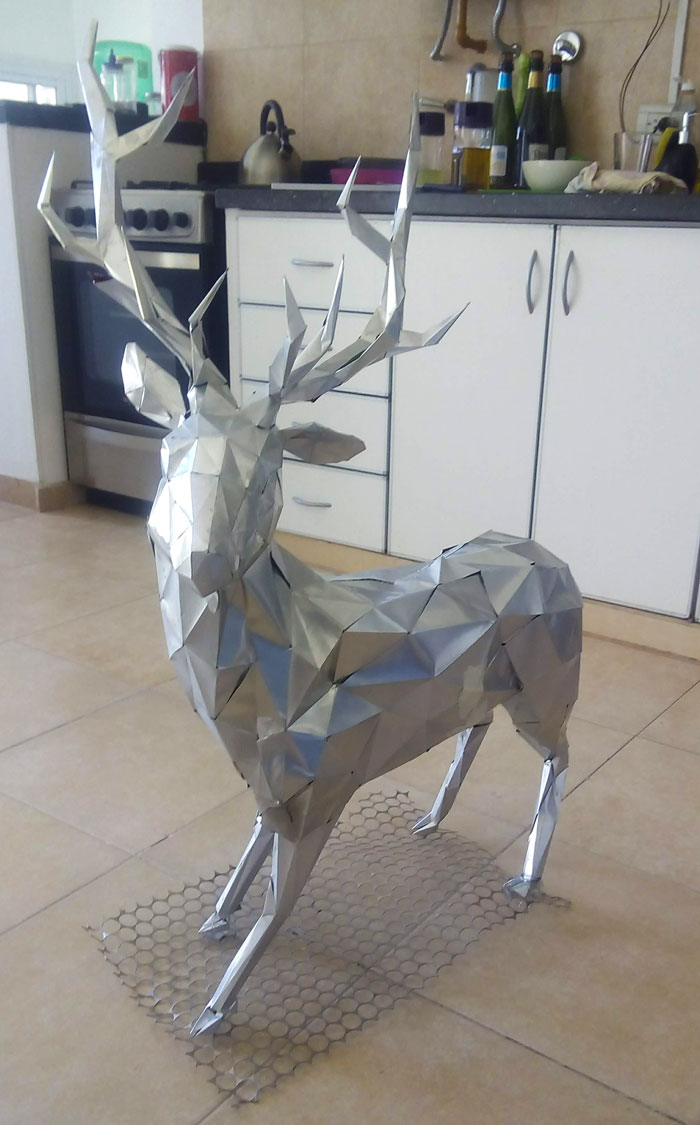 Geometric DIY Christmas deer decoration made of metallic paper standing on a kitchen floor.