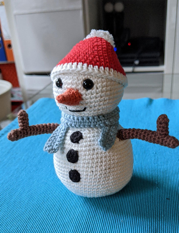 Crocheted snowman with a red hat and blue scarf, perfect for Creative DIY Christmas decorations.