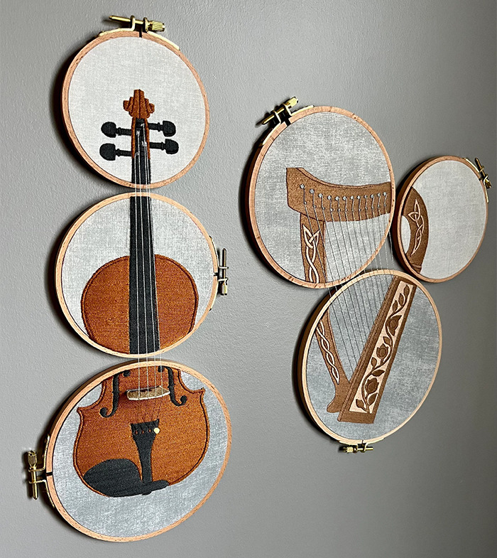 Creative embroidery featuring violin and harp designs in wooden hoops.