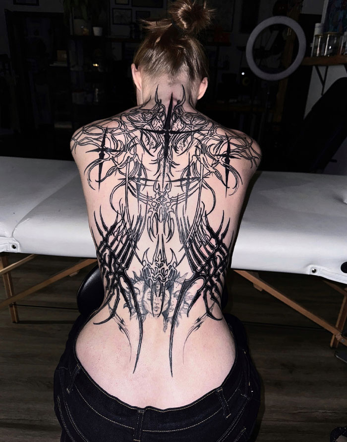 Tattoo of intricate cybersigilism design on person's back, showcasing unique symbolism and style.