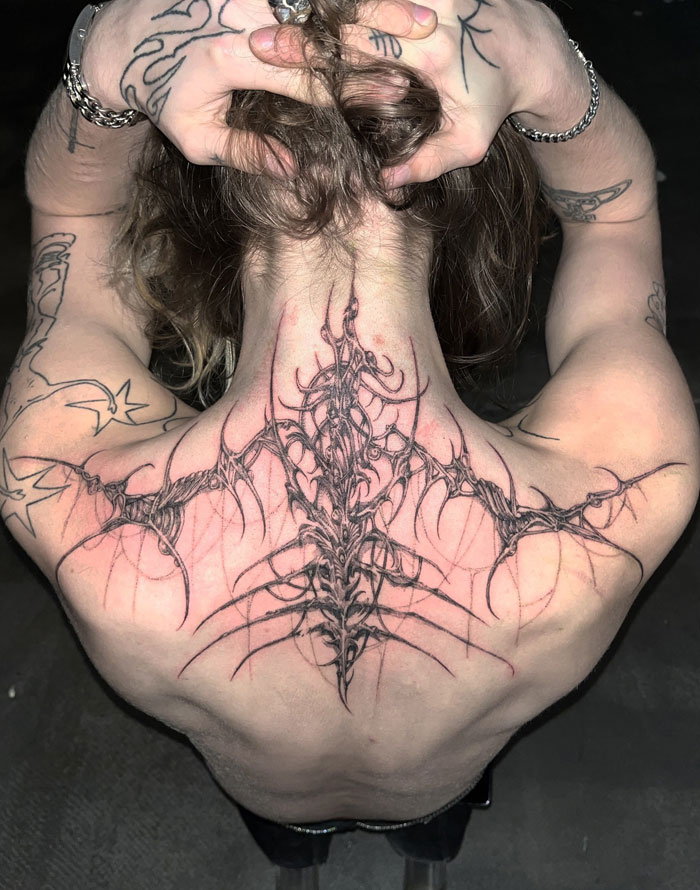 Tattoo showcasing cybersigilism style with intricate, symbolic design on a person's back.