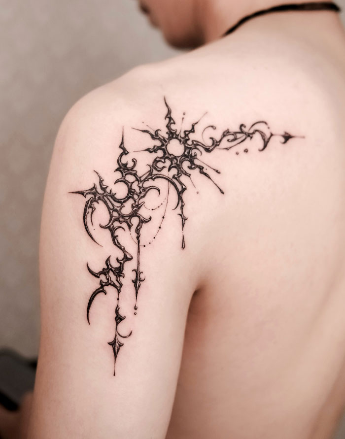 Tattoo featuring intricate cybersigilism design on a person's shoulder, showcasing bold, symmetrical patterns.