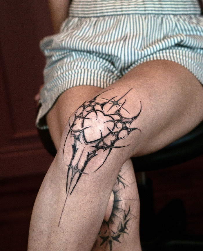 Cybersigilism tattoo design on knee, featuring intricate lines and symbolic patterns.