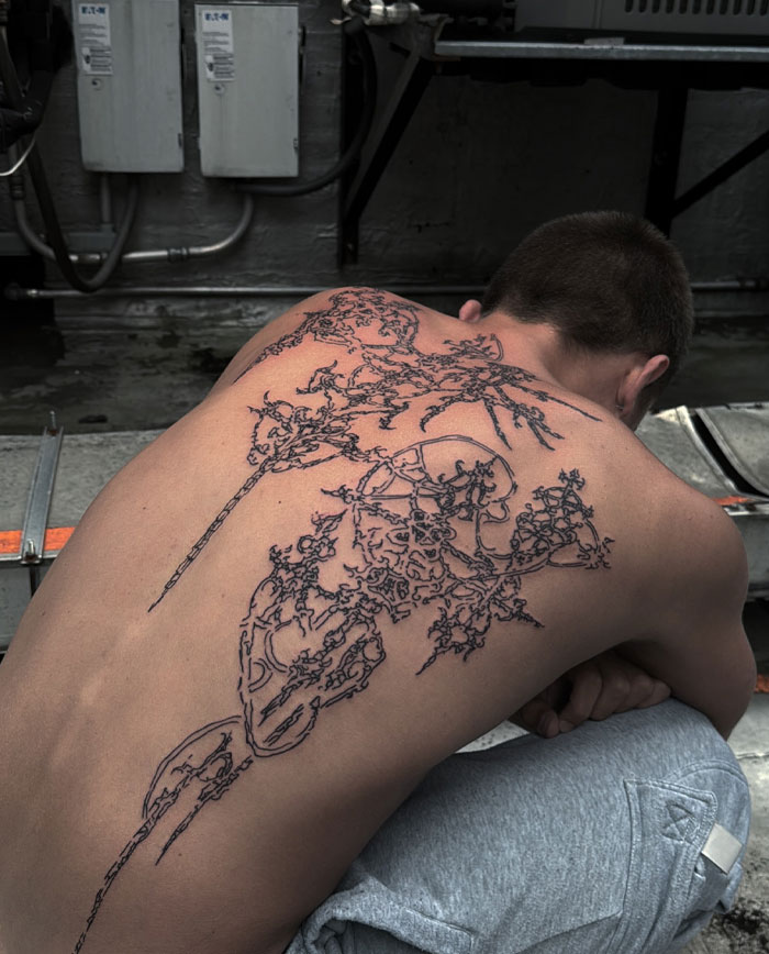 Man with intricate cybersigilism tattoo on his back, showcasing unique symbolism and artistic style.