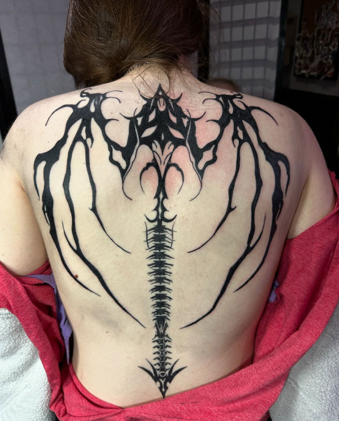 Tattoo of intricate cybersigilism design on back, featuring bold black lines and symmetrical patterns.