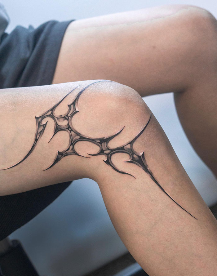 Tattoo with cybersigilism design on a person’s knee, showcasing intricate black geometric symbolism.