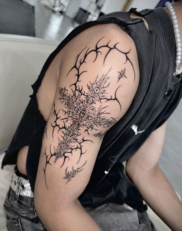 Cybersigilism tattoo design on arm, featuring intricate symbolic patterns in black ink.