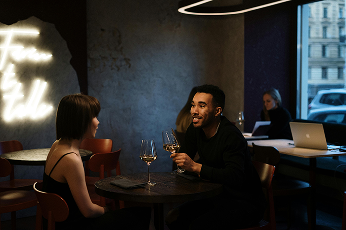 Couple on a Bumble date at a restaurant with wine glasses on the table.
