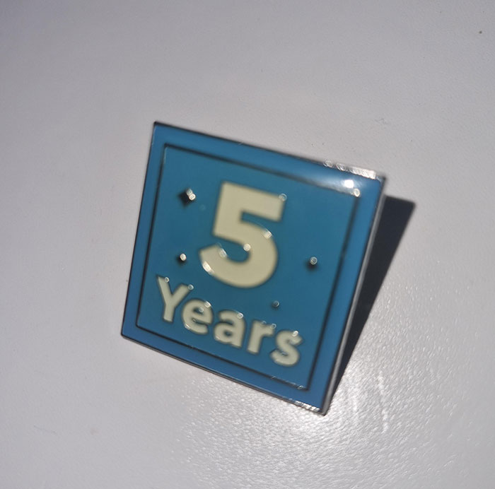 5-year milestone pin on white surface, symbolizing disappointing presents gifts.