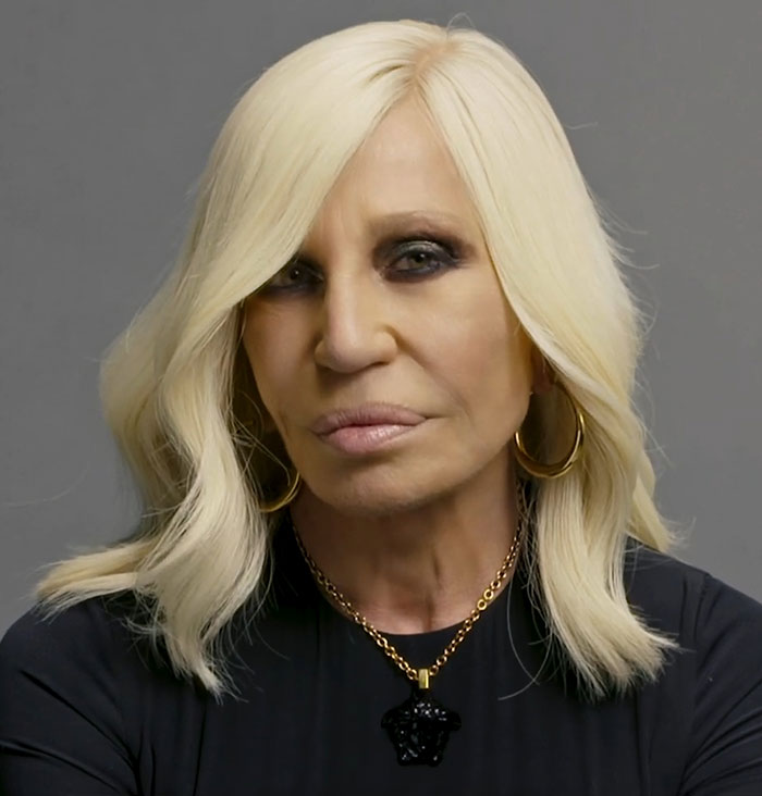 Blonde woman with long hair and gold necklace at musical premiere.