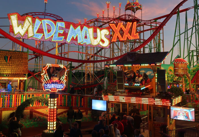 "Wilde Maus XXL roller coaster at a theme park, vibrant lights glowing in the evening."