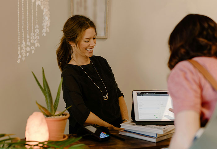 A customer interacting with a smiling store assistant at the counter, highlighting customer service moments.