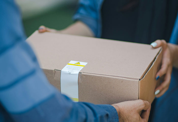 Hands exchanging a cardboard box, referencing customer service interaction.