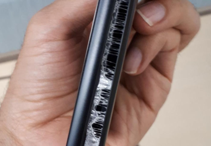 Hand holding a damaged smartphone with a c*****d screen, illustrating a customer query.