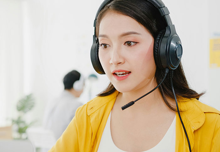 Customer service representative with headset, ready to assist, in a bright office setting.