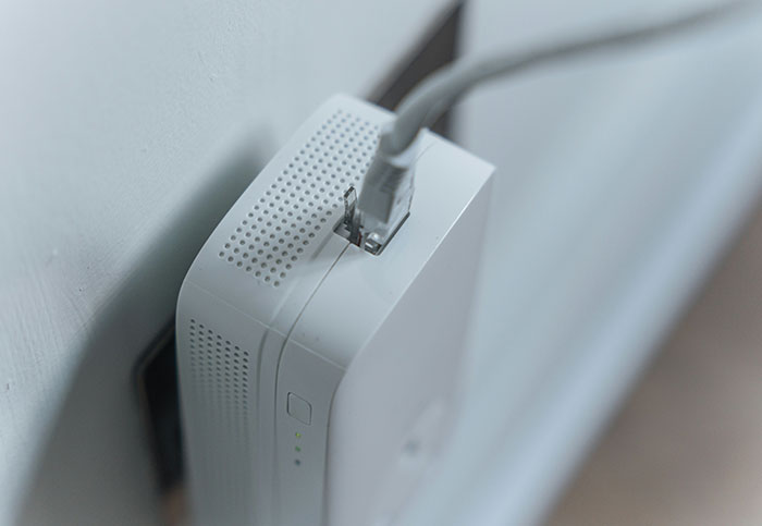 White Wi-Fi router plugged into wall, representing tech customer inquiries.