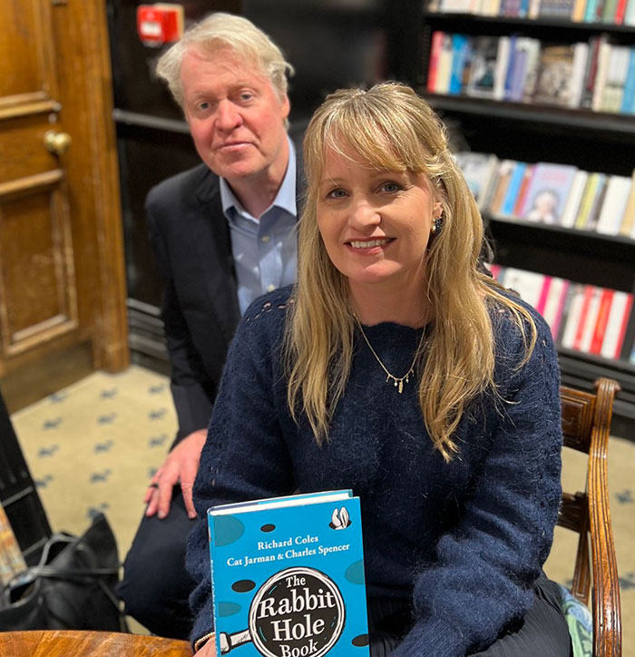 Two people in a bookstore, one holding "The Rabbit Hole Book" by Richard Coles, Cat Jarman, Charles Spencer.