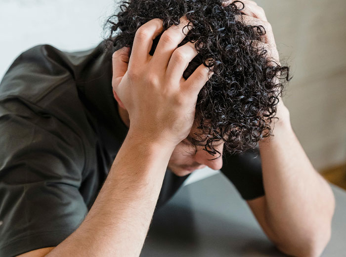 Frustrated dad sitting at a table with his hands on his head, struggling to handle parenting challenges.