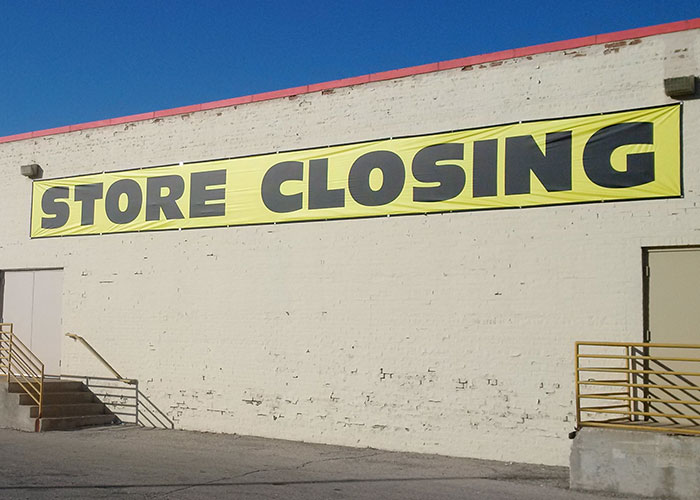 Yellow banner on a brick wall reading "Store Closing," illustrating CEO management failures.