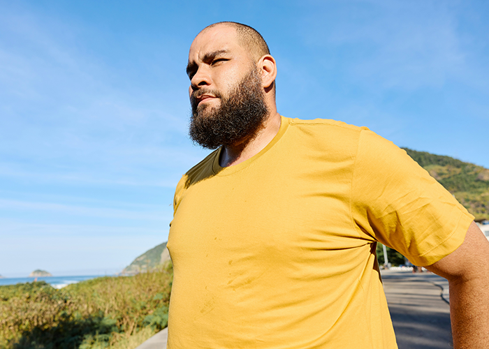 Man in a yellow shirt standing outdoors, embodying confidence despite fat-shaming issues. Man in a yellow shirt standing outdoors, embodying confidence despite fat-shaming issues.