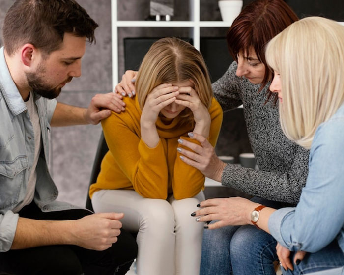 A group comforting a distressed woman after conflict involving father and daughter issues.