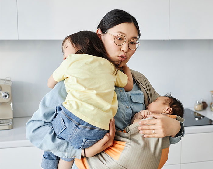 A mother holds her children in a kitchen, evoking the realization of family sacrifices.