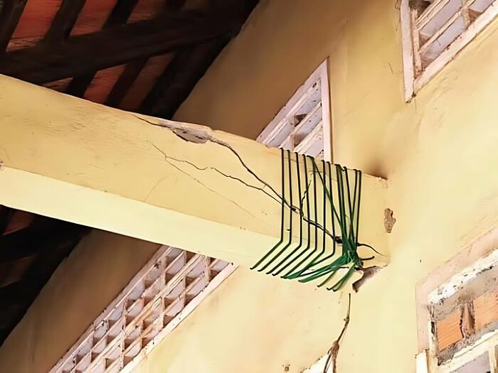 Construction fail: c*****d beam haphazardly repaired with green strings in a yellow room.
