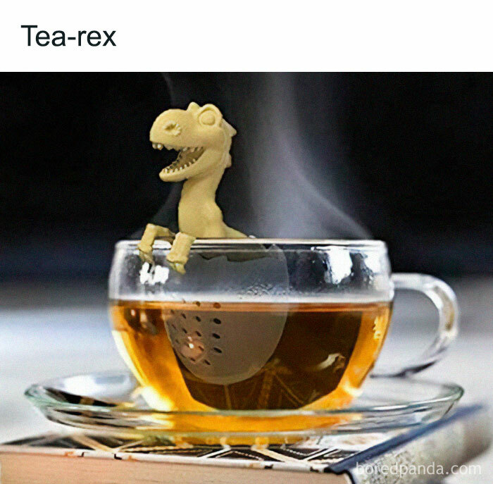 Dinosaur tea infuser shaped like a T-rex in a steaming cup, illustrating a humorous prehistoric twist on tea time.