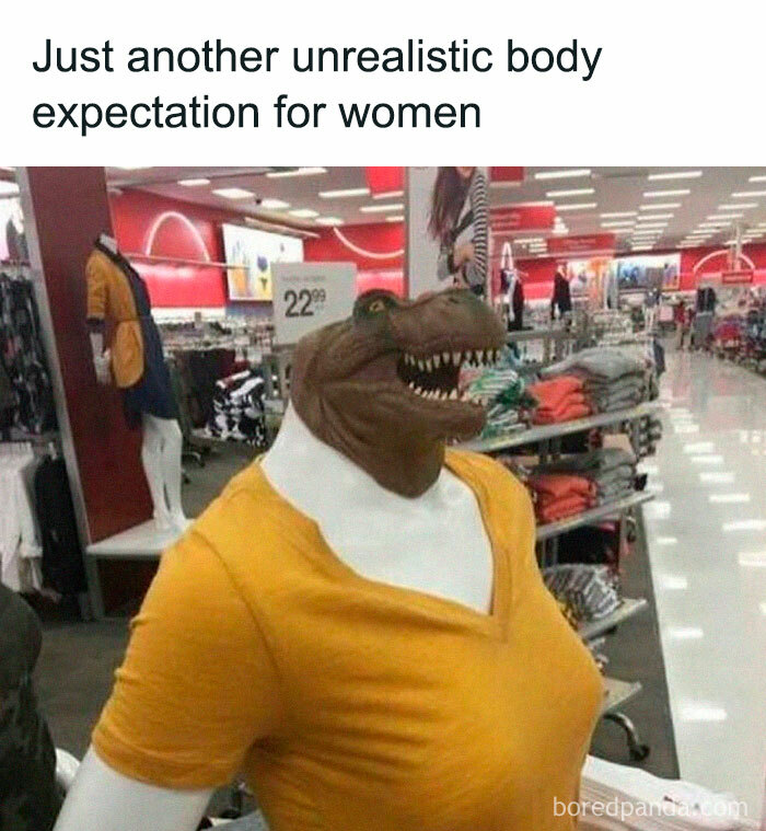 A dinosaur mannequin wearing a yellow shirt in a store, humorously mocking unrealistic body standards.