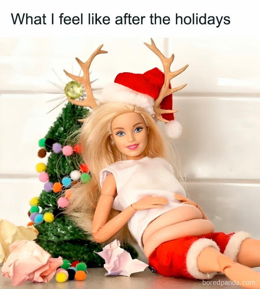 Doll in Santa outfit with antlers, sitting by a Christmas tree, humorously mimics post-holiday feeling, encapsulating funny Christmas memes.