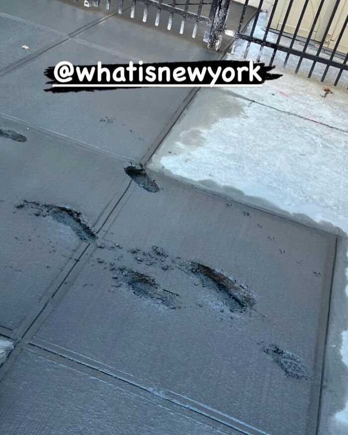 Wet cement on a New York sidewalk with footprints, capturing a funny urban moment.