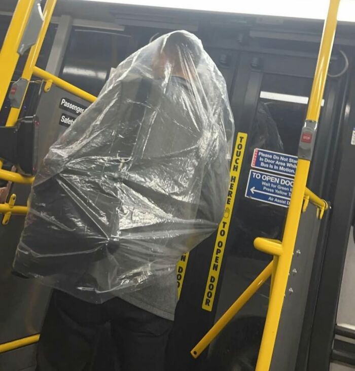 Person in New York subway covered in plastic, creating a humorous scene.