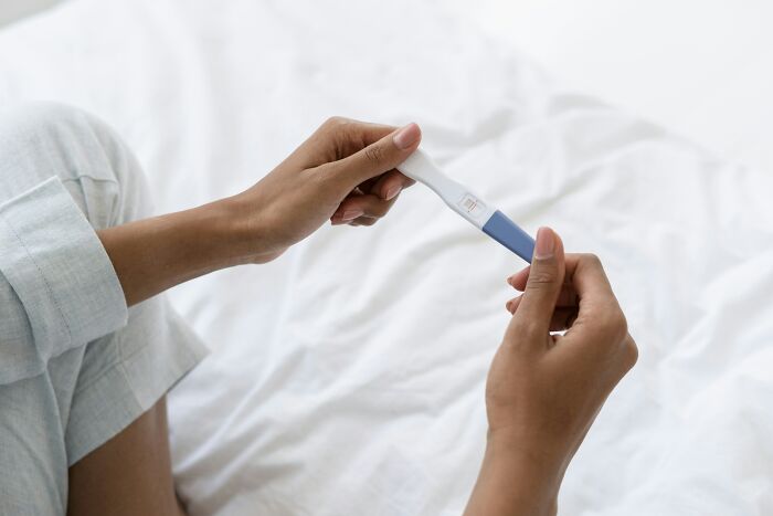 A person holding a pregnancy test, reflecting on secrets kept from loved ones.