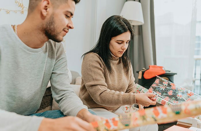 Woman wrapping gifts at home, inspecting tags carefully.