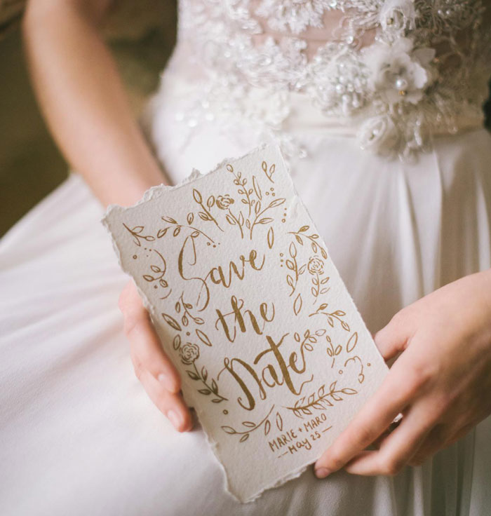 "Close-up of a bride holding a 'Save the Date' card in her hands, related to destination wedding struggles. "Close-up of a bride holding a 'Save the Date' card in her hands, related to destination wedding struggles.