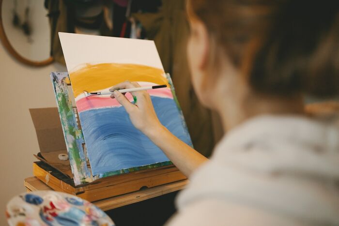 Person painting colorful abstract art at a table, focusing on creative expression during a work Christmas party.