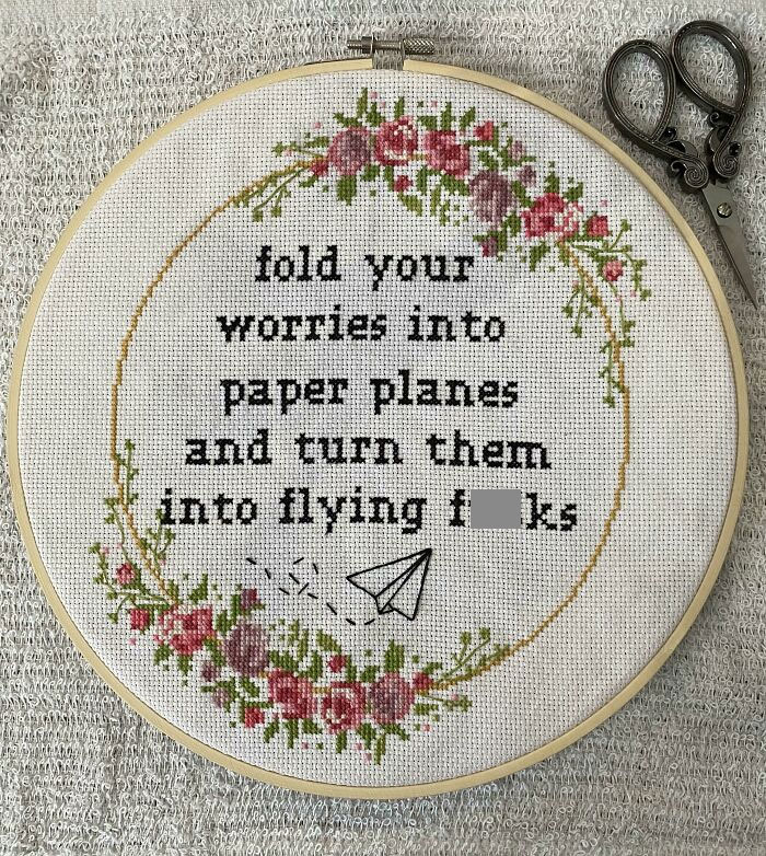 Embroidery hoop with humorous text for trolling Christmas gifts, featuring flowers and a paper plane.