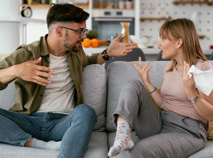 A couple arguing on the couch about kids and family issues, with emotional expressions and gestures.