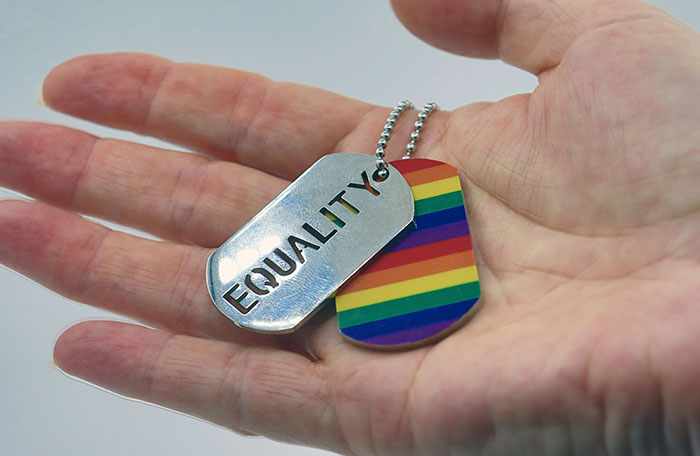 Hand holding Equality and rainbow flag dog tags, symbolizing LGBTQ+ support.