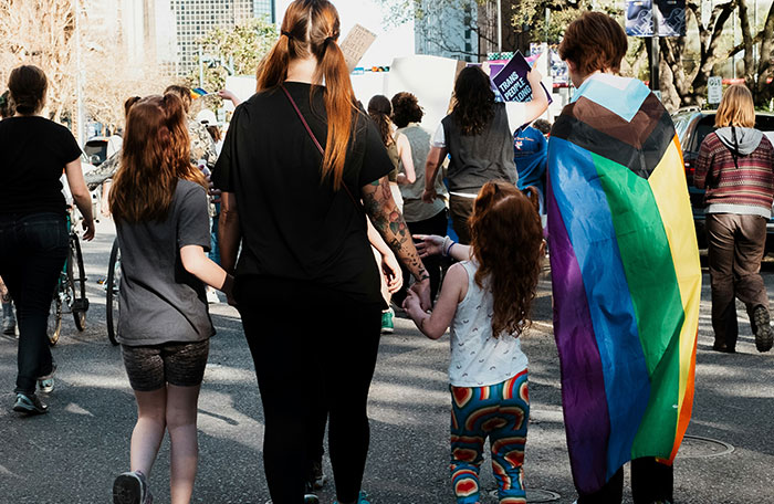 Family at a pride event with a rainbow flag, highlighting gay aunt's influence.