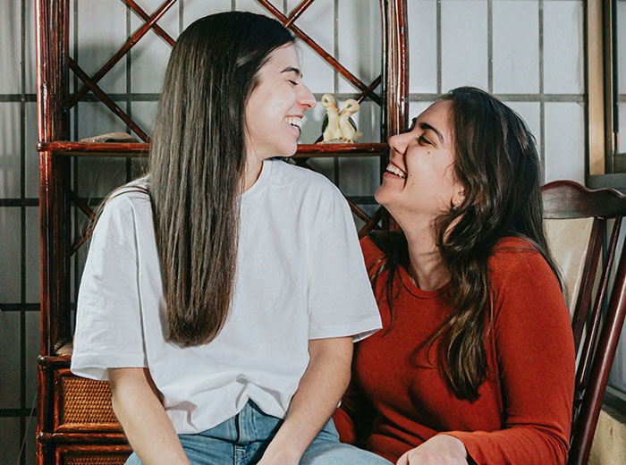 Two women smiling at each other at home, representing a supportive bond with family diversity.