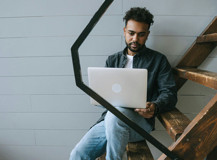 Man sitting on stairs with a laptop, representing son-in-law's stair-sitting habit.