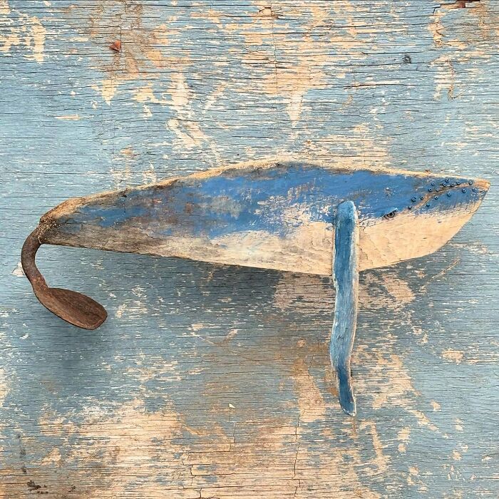 Driftwood animal sculpture resembling a blue whale by Kirsty Elson on a textured background.