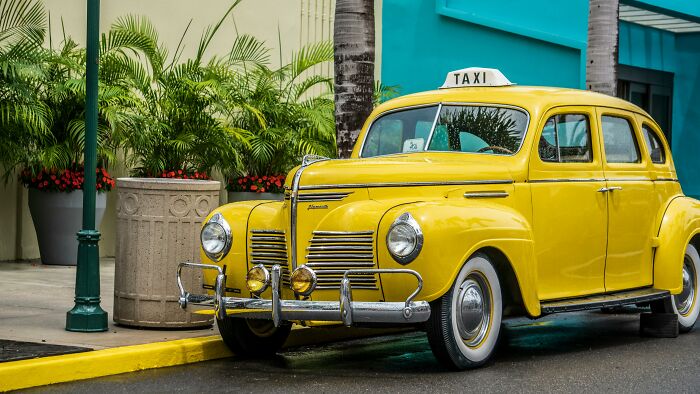 Vintage yellow taxi parked on the street, representing industries built on fooling people.