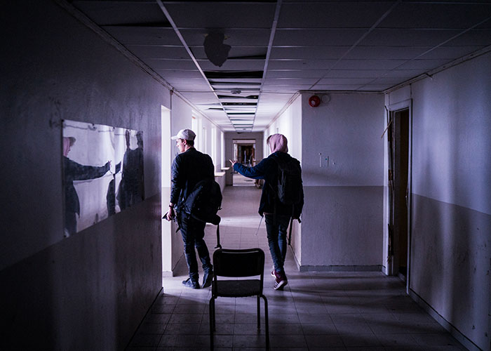 Two people exploring a dim hospital corridor, evoking cinematic atmosphere.